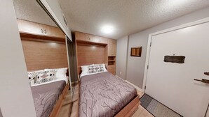 Ein Schlafzimmer mit Bett, Holz-Kopfteil, Einbauschrank und einer Tür.