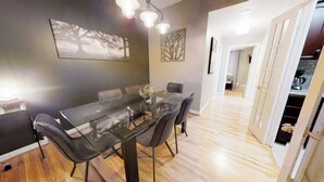 A modern dining area with a glass table, black chairs, and a vase of flowers. There is a painting on the wall and a staircase leading to another room. - Centrally Located 3-BR Condo in DT Toronto (Toronto)