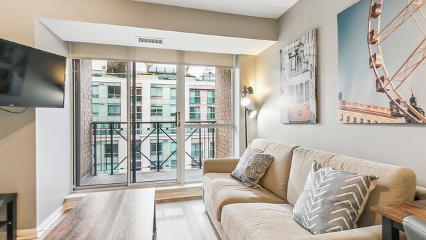A modern living room with a sofa, a coffee table, and a TV mounted on the wall. - Modern 1-BR Condo DT Toronto (Toronto)
