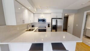 A modern kitchen with white cabinets, stainless steel appliances, and a central island.