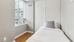 A small, modern bedroom with a bed, a window, and a sliding door. - Modern 1+1-BR Condo DT Toronto (Toronto)