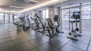 A modern gym with various cardio machines, large windows, and a clean, tiled floor. - Modern 1+1-BR Condo DT Toronto (Toronto)