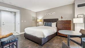Une chambre d’hôtel avec un lit, une commode, une table ronde et une chaise.