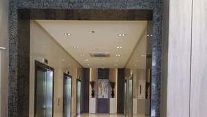 Moderni hotellin aula, jossa on kiillotettu marmorilattia, vastaanottotiski ja hissit.