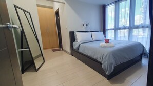 Moderni hotellihuone, jossa on sänky, vaatekaappi ja suuri ikkuna.