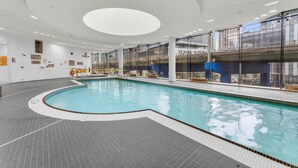 An indoor swimming pool with a curved design, surrounded by glass walls and a tiled floor. - Amazingly Spacious 2-BR Condo in DT Toronto (Toronto)