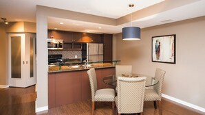 A modern kitchen with stainless steel appliances, a glass island, and two patterned chairs at a glass table. - Amazingly Spacious 2-BR Condo in DT Toronto (Toronto)
