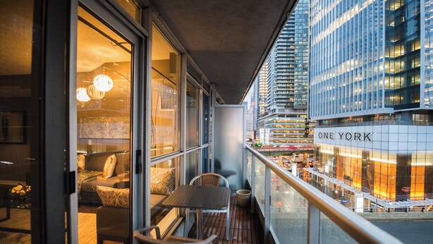 A balcony with a view of One York building, furnished with a table and chairs, and a hanging light fixture. - Amazingly Spacious 2-BR Condo in DT Toronto (Toronto)