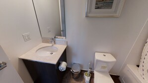 A bathroom with a sink, toilet, and a trash can. - Fully-Equipped 3-BR Condo in DT Toronto (Toronto)