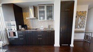 A modern kitchen with dark cabinetry, a stainless steel range hood, and a built-in oven. - Fully-Equipped 3-BR Condo in DT Toronto (Toronto)