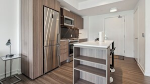 A modern kitchen with stainless steel appliances, wooden cabinetry, and a white countertop. - Lovely 1-BR in DT Toronto (Toronto)