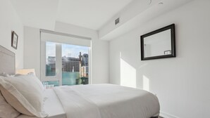 A modern hotel room with a large bed, a city view through a sliding door, and a black-framed mirror on the wall. - Lovely 1-BR in DT Toronto (Toronto)