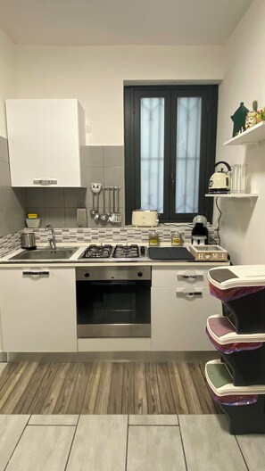 A modern kitchen with white cabinets, a gas stove, a toaster, and a window with curtains. - Charming 2-bedroom apartment in nice Catania with AC, WiFi (Catania)