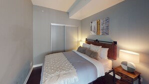 A bedroom with a bed, bedside lamps, a nightstand, a wardrobe, and decorative wall art. - Modern Central 1-BR Condo in DT Toronto (Toronto)