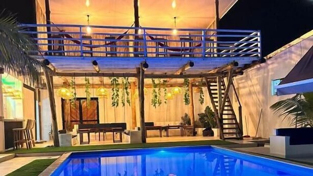 A swimming pool with a covered deck area, outdoor furniture, and a staircase leading to an upper level. - Hotel All In One  (Armenia)