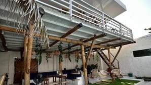 A modern outdoor seating area with a covered patio, artificial grass, and a staircase leading to an upper level. - Hotel All In One  (Armenia)