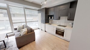 A modern kitchen with grey cabinets, a built-in oven, and a large window. - Modern Central 1+1-BR Condo in DT Toronto (Toronto)