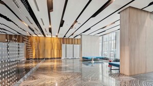 A modern lobby with a polished marble floor, a seating area with blue and red chairs, and a wooden wall with circular patterns. - Modern Central 1-BR Condo in DT Toronto (Toronto)