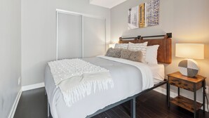 A bedroom with a bed, nightstand, wall art, and a sliding door. - Modern Central 1-BR Condo in DT Toronto (Toronto)