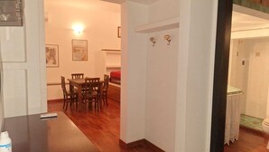 Un coin repas avec une table et des chaises en bois, un canapé rouge et un luminaire fixé au mur.