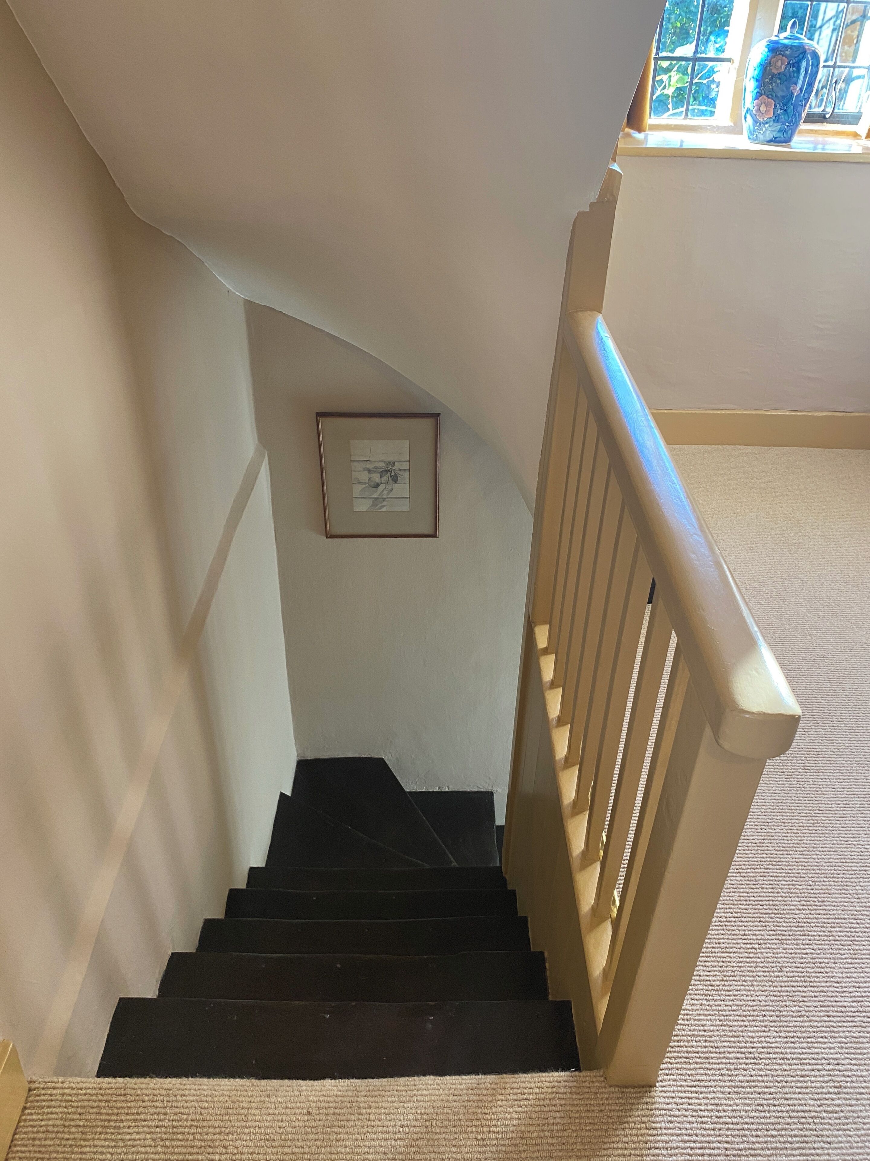 Eine Treppe mit schwarzer Handlauf und einem Bildrahmen an der Wand.
