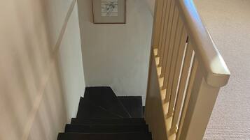 Eine Treppe mit schwarzer Handlauf und einem Bildrahmen an der Wand.