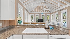 A kitchen with granite countertops, white cabinets, and a ceiling fan. - Carillon Beach - Grits Carlton by PHG (Panama City Beach)