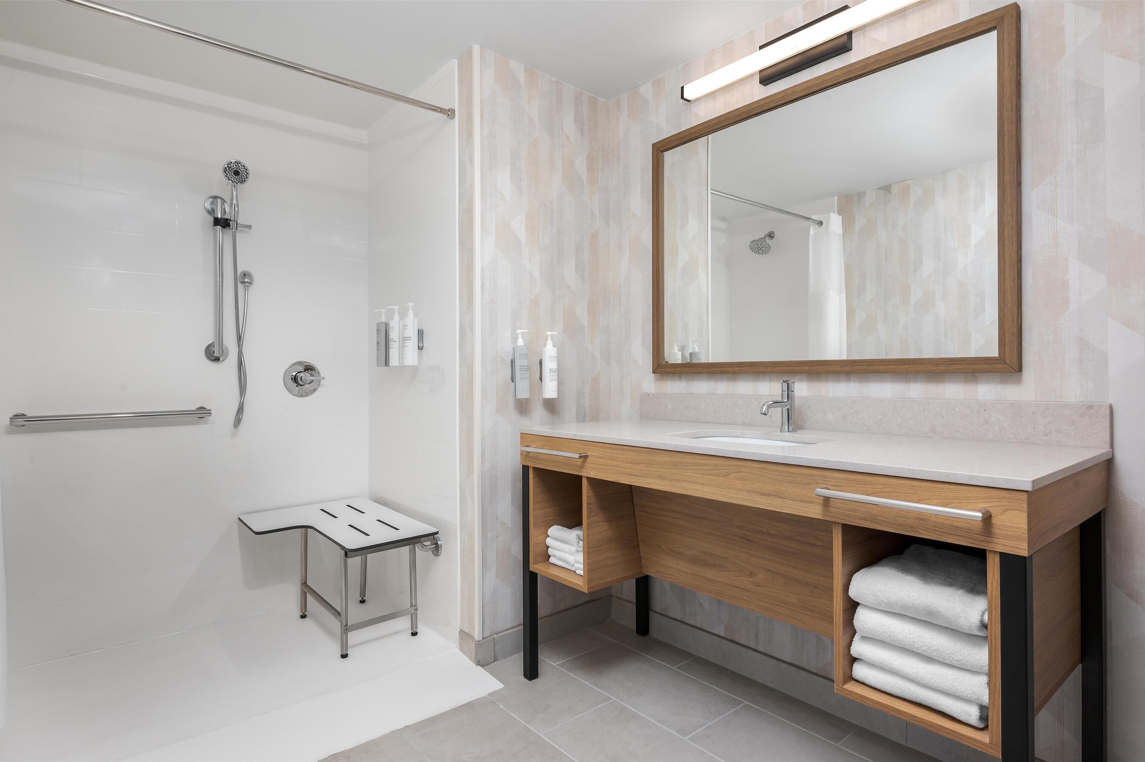 A modern bathroom with a shower, vanity, and a large mirror.