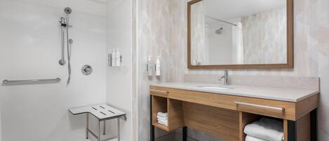 A modern bathroom with a shower, vanity, and a large mirror.