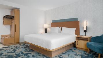 Una habitación de hotel moderna con una cama grande, un armario, una mesita de noche y una silla.