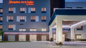 A modern hotel exterior with a prominent sign reading "Hampton Inn & Suites by Hilton."