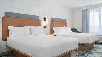 A hotel room with two beds, a nightstand, a lamp, and a window with curtains.