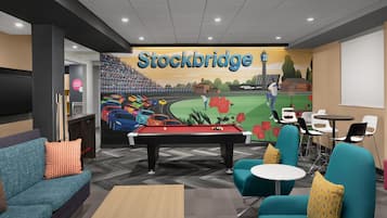 A pool table in a lounge area with teal chairs and a billiards table.