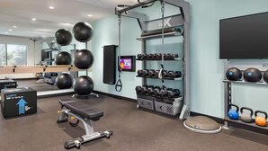 Un gimnasio con equipamiento de ejercicio, un saco de boxeo y una pantalla de televisión.