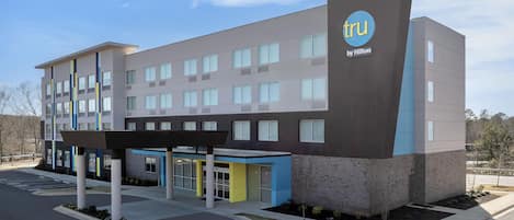 A modern hotel building with a flat roof, multiple windows, and a sign indicating it's by Hilton.