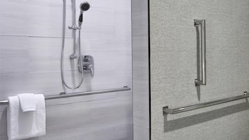 Un baño moderno con cabina de ducha de vidrio, un perchero y una puerta de cristal.