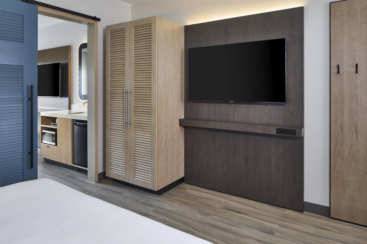 Eine moderne Küche mit Holzausstattung, einem eingebauten Backofen und einem flachbildfernseher an der Wand.