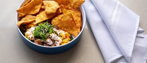 En skål mad med chips og en serviet på et bord.