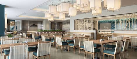 Ein geräumiges Restaurant mit hohen Decken, modernen Pendelleuchten und verschiedenen Sitzgelegenheiten, darunter Tische und Stühle.