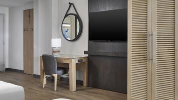 Hotellihuoneessa on puinen työpöytä, tuoli, seinälle asennettu televisio ja vaatekaappi, jossa on vaakasuorat säleet.