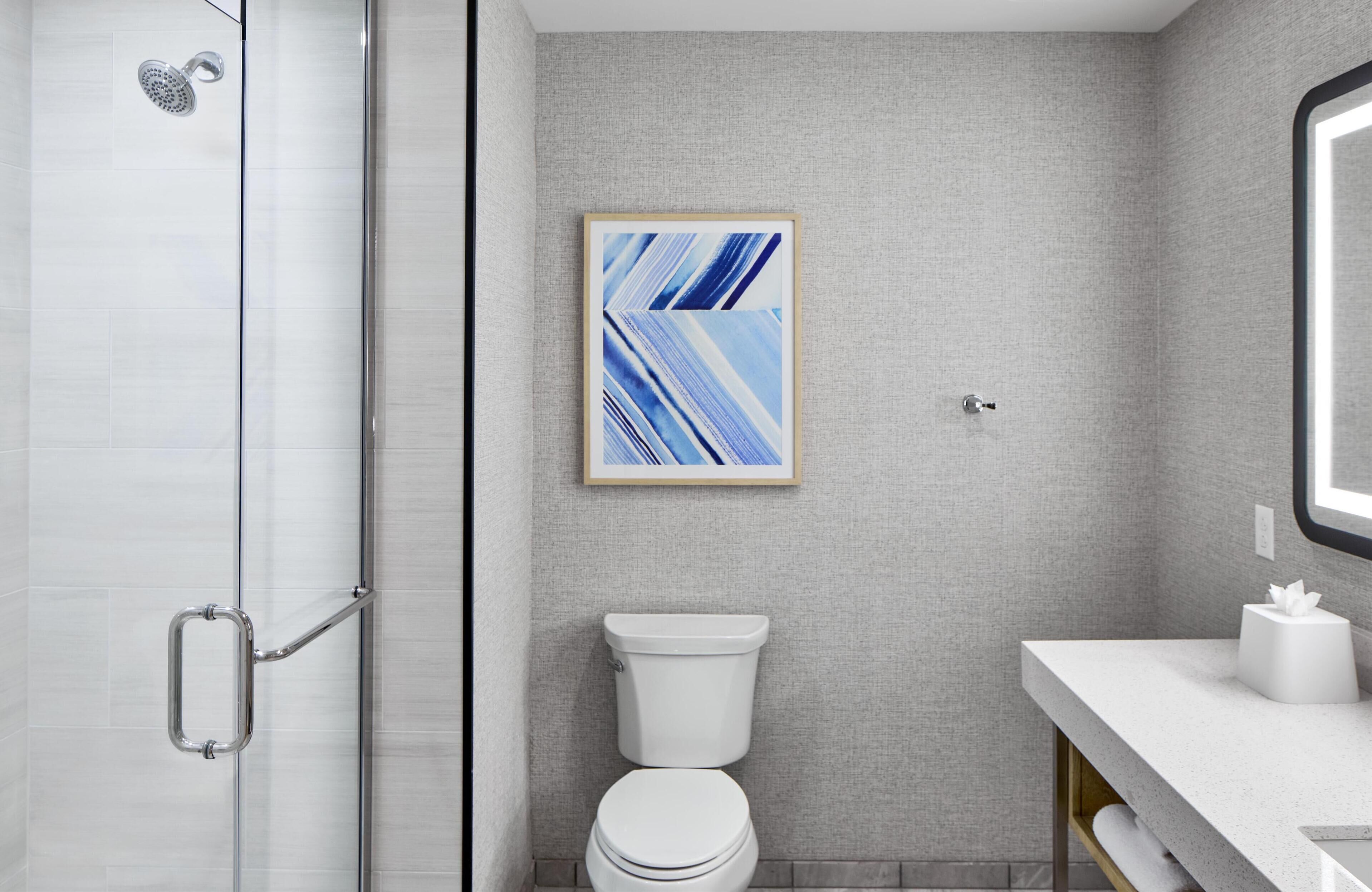 Une salle de bain moderne avec une douche à parois de verre, des toilettes et un lavabo avec un miroir.