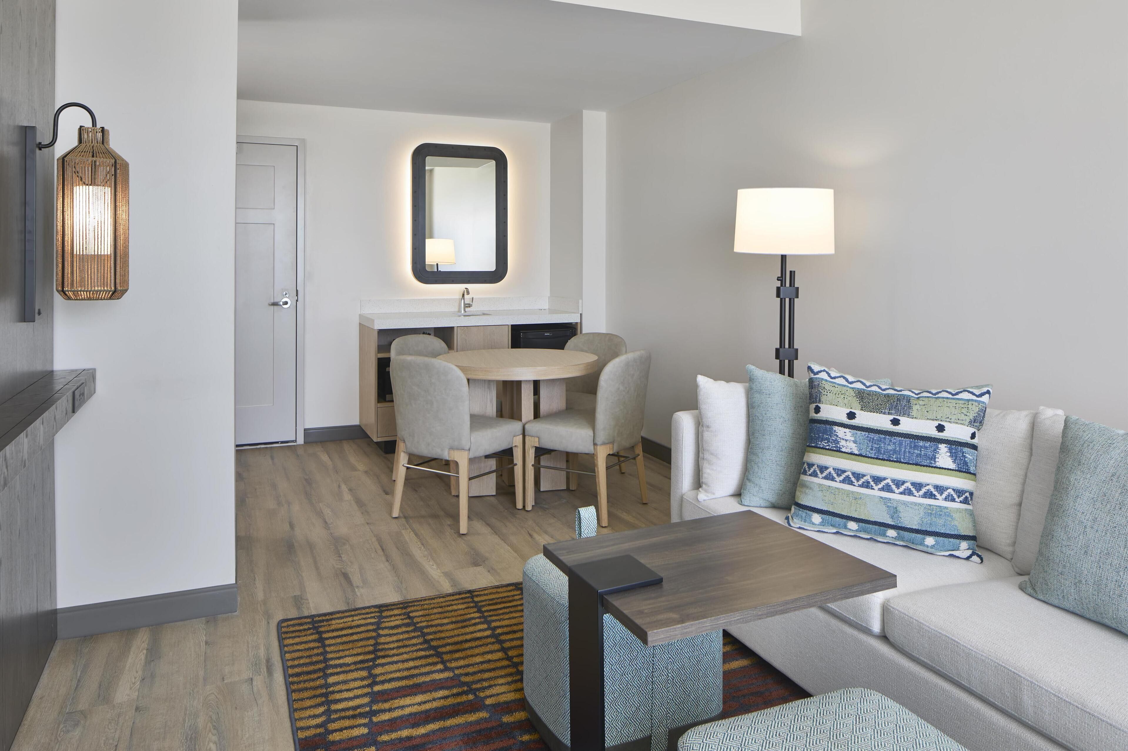 A modern living room with a sofa, a coffee table, and a dining area with a table and chairs.
