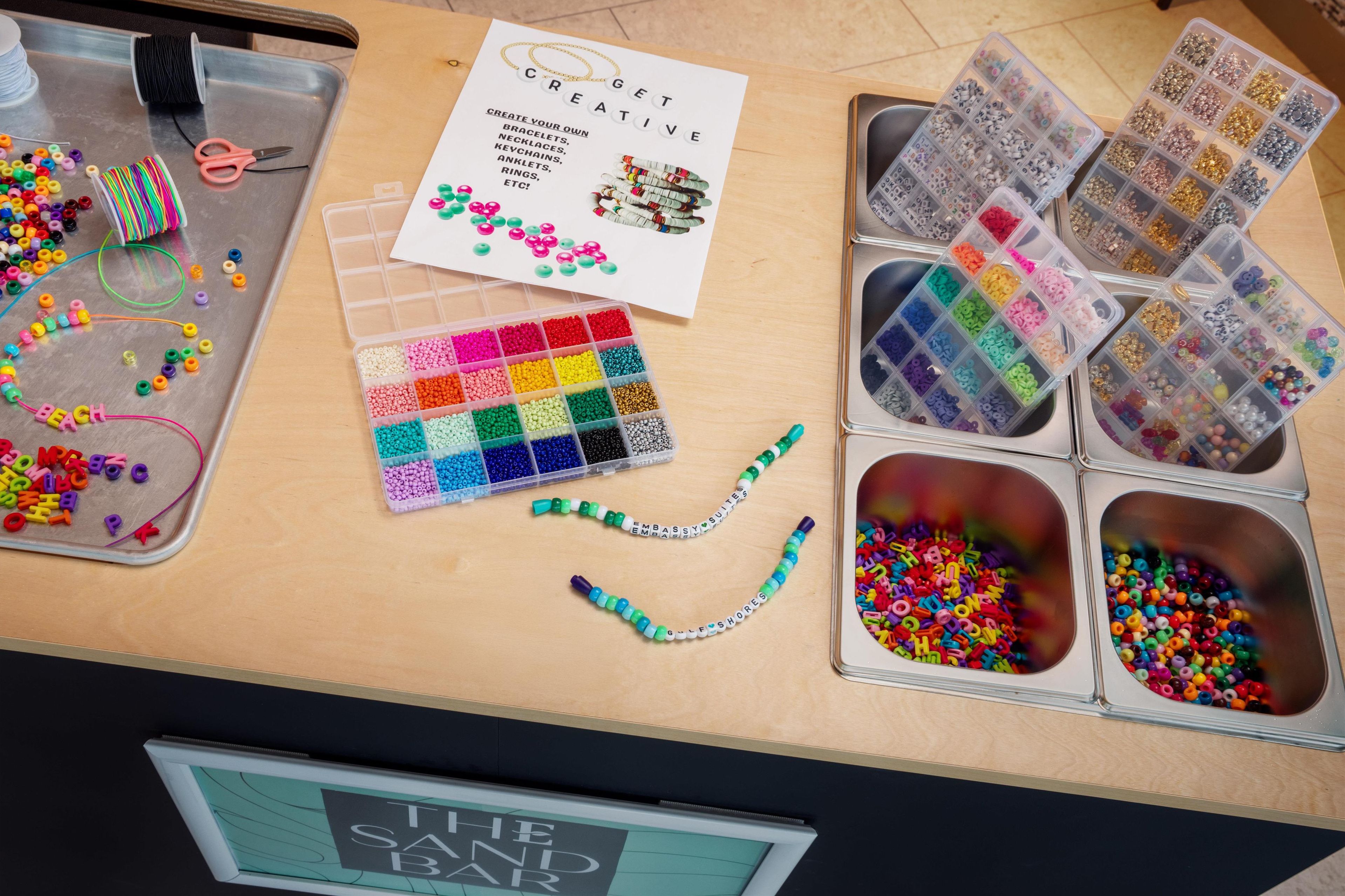 A crafting table with various beads, spools of thread, and a sign encouraging creativity.