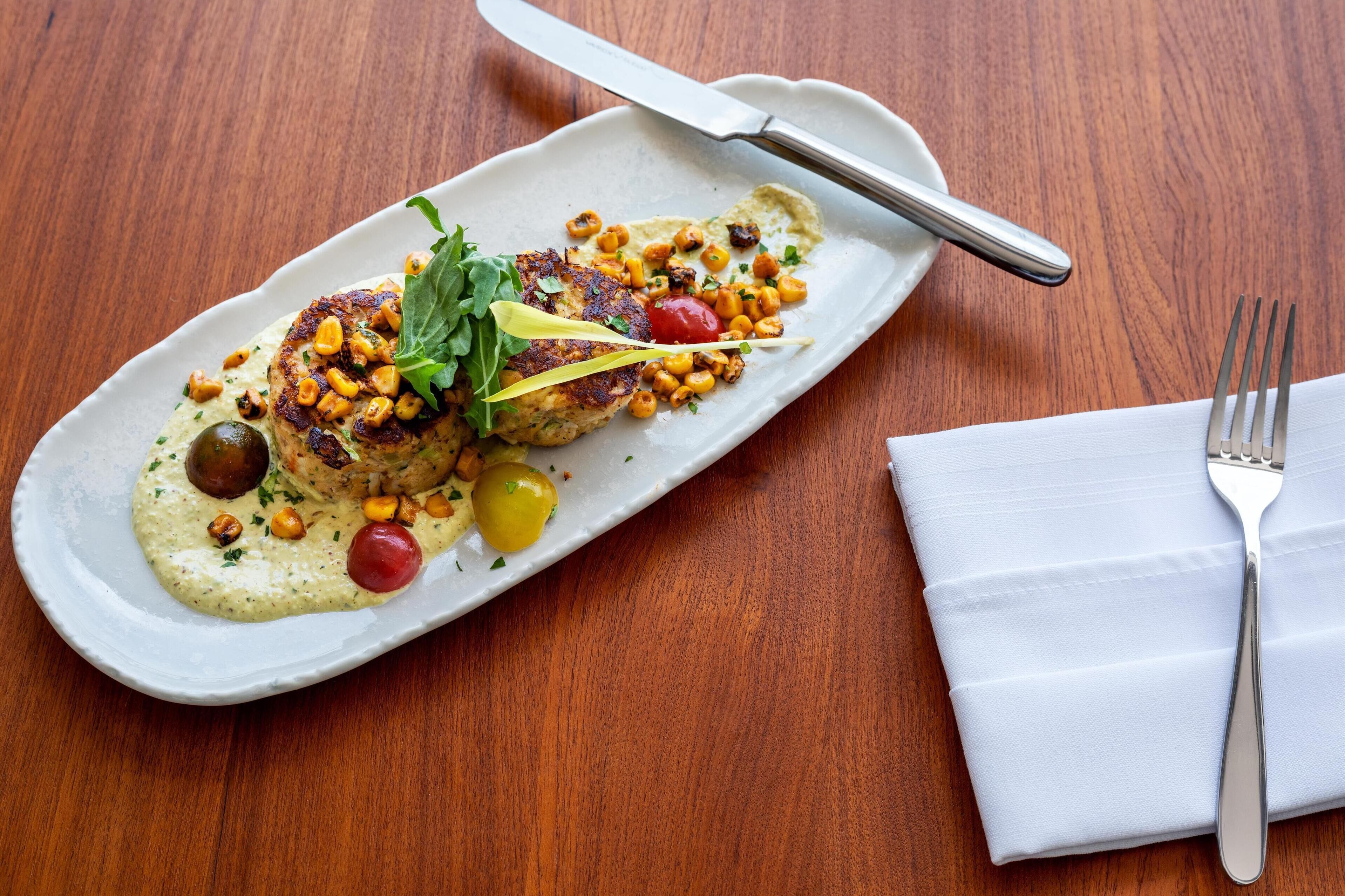 A plate of food with a knife and fork on a wooden table.