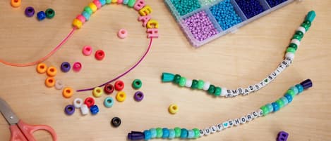 Un espace de travail avec des perles, des lettres et une paire de ciseaux sur une surface en bois.