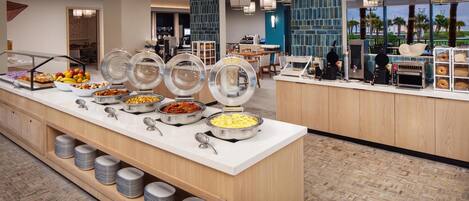 A buffet area with various food items and a counter with a coffee machine.