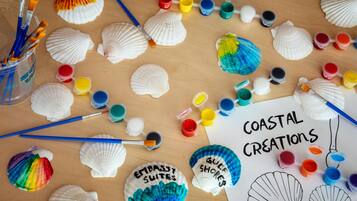 A table with painted seashells, paintbrushes, and paint containers.