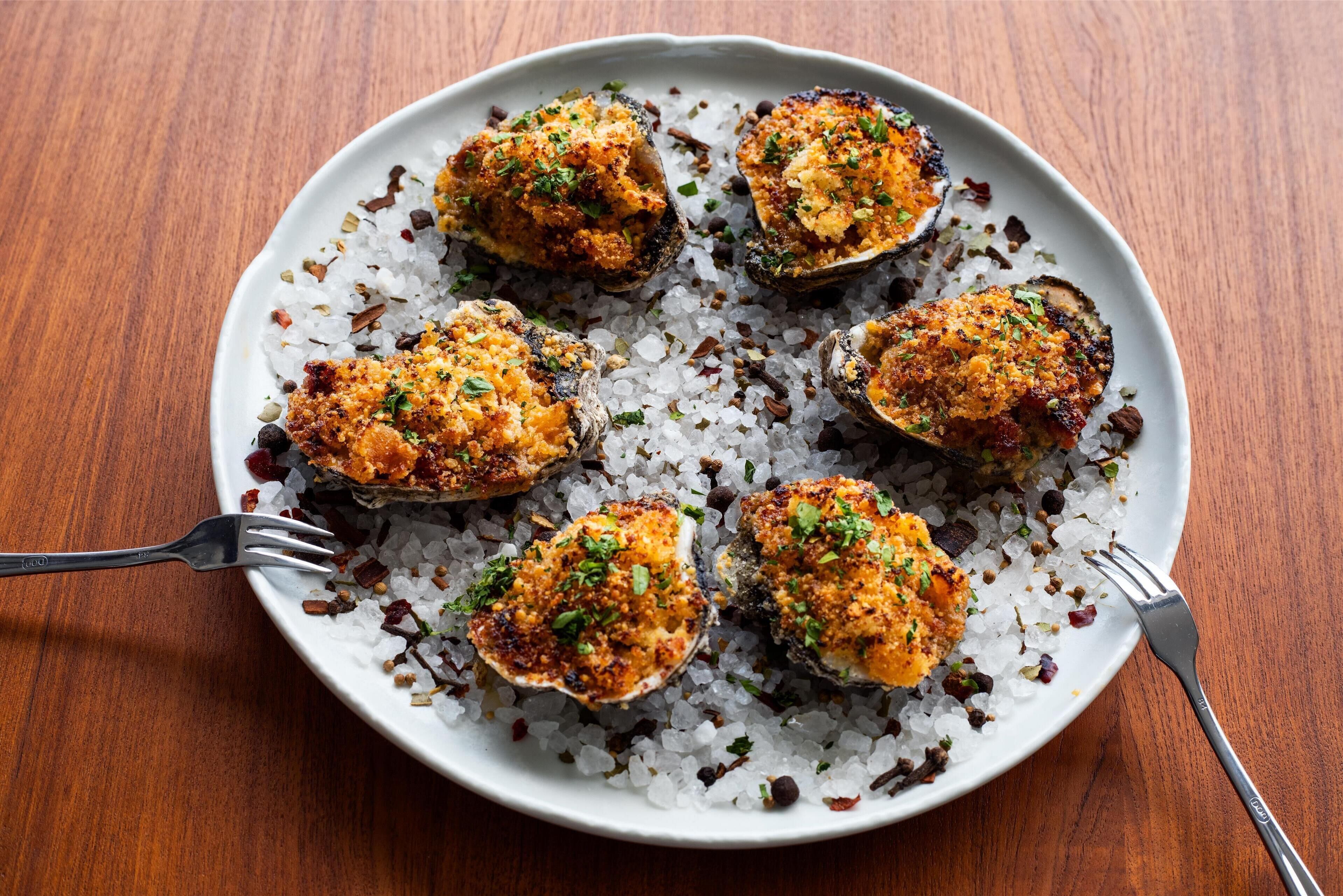 A plate of stuffed mushrooms garnished with herbs, served on a bed of rice and scattered with spices.