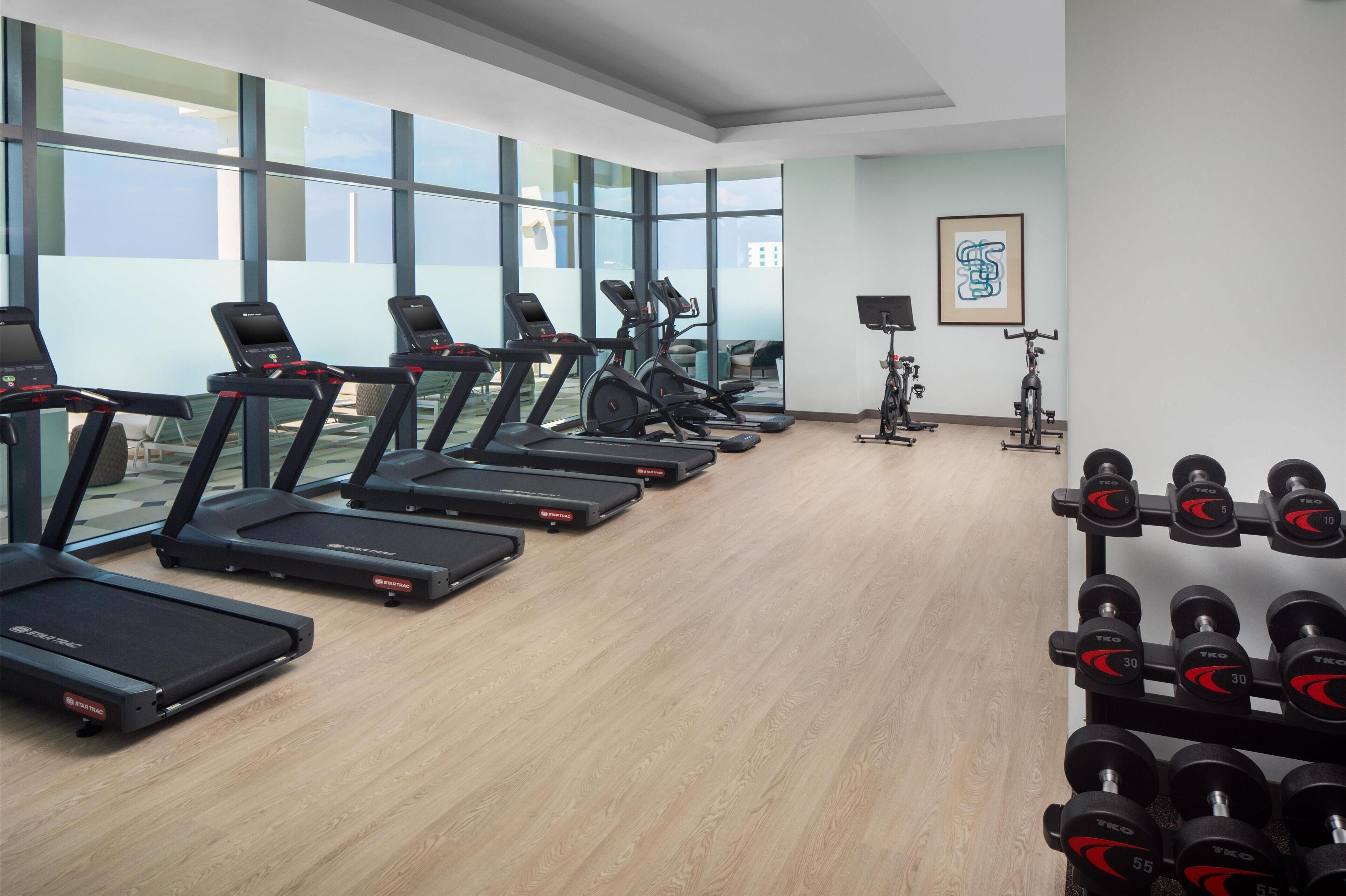A gym with treadmills, stationary bikes, and dumbbells.