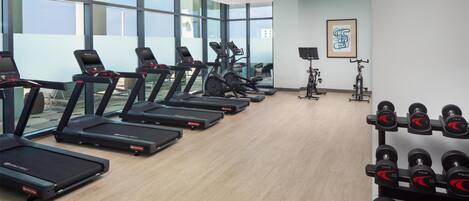 A gym with treadmills, stationary bikes, and dumbbells.